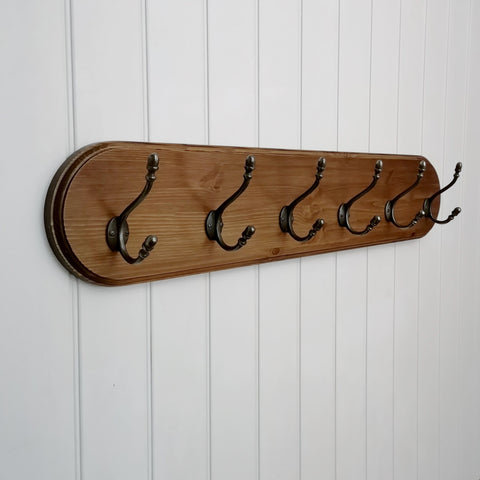 Antique pine finished coat rack with curved edges and cast iron hooks